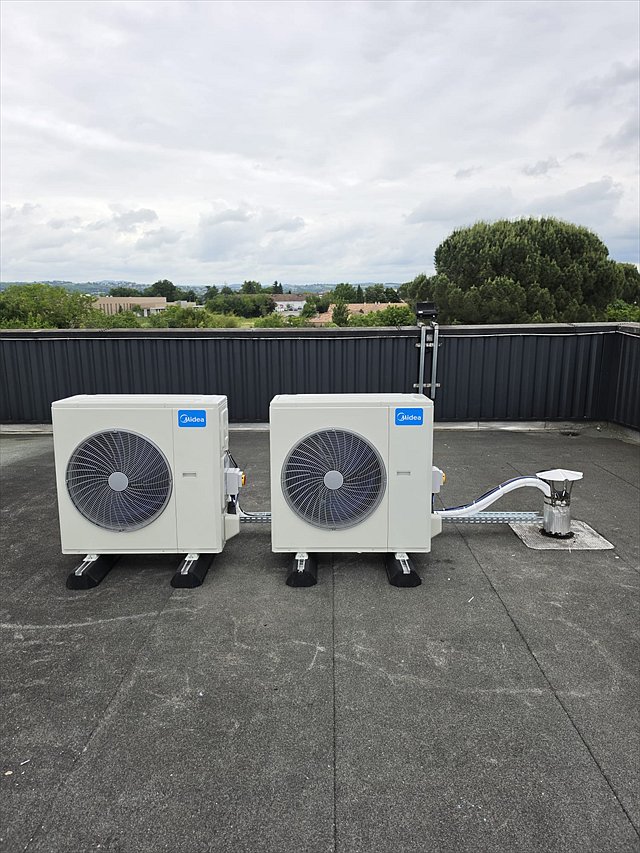 Deux groupes extérieurs de climatisation installés en toiture-terrasse sur plots antivibratiles